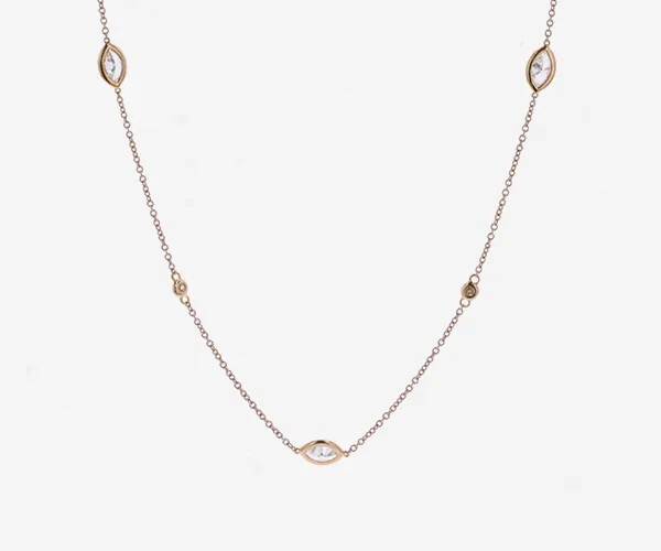 A yellow gold diamond bezel necklace on grey brackgound