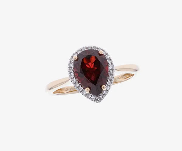 A yellow gold pear cut red garnet with with diamonds on grey brackgound