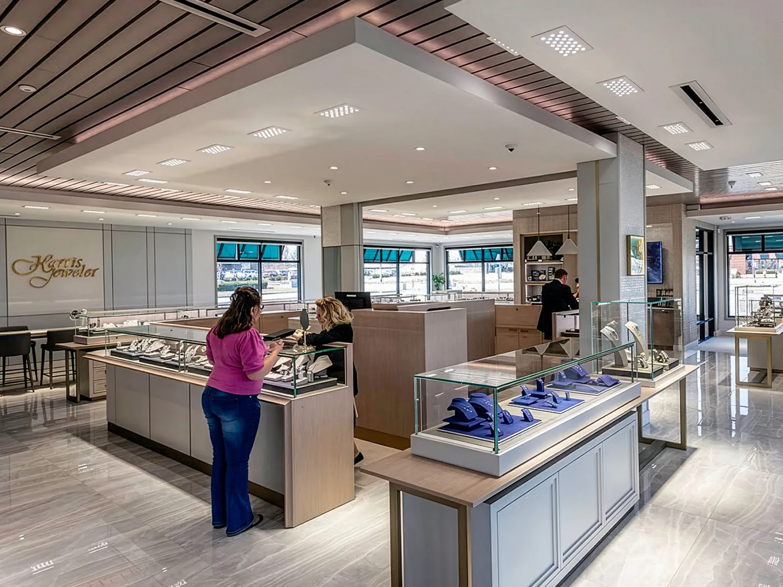 Interior of a modern jewelry store with display cases and customers browsing.
