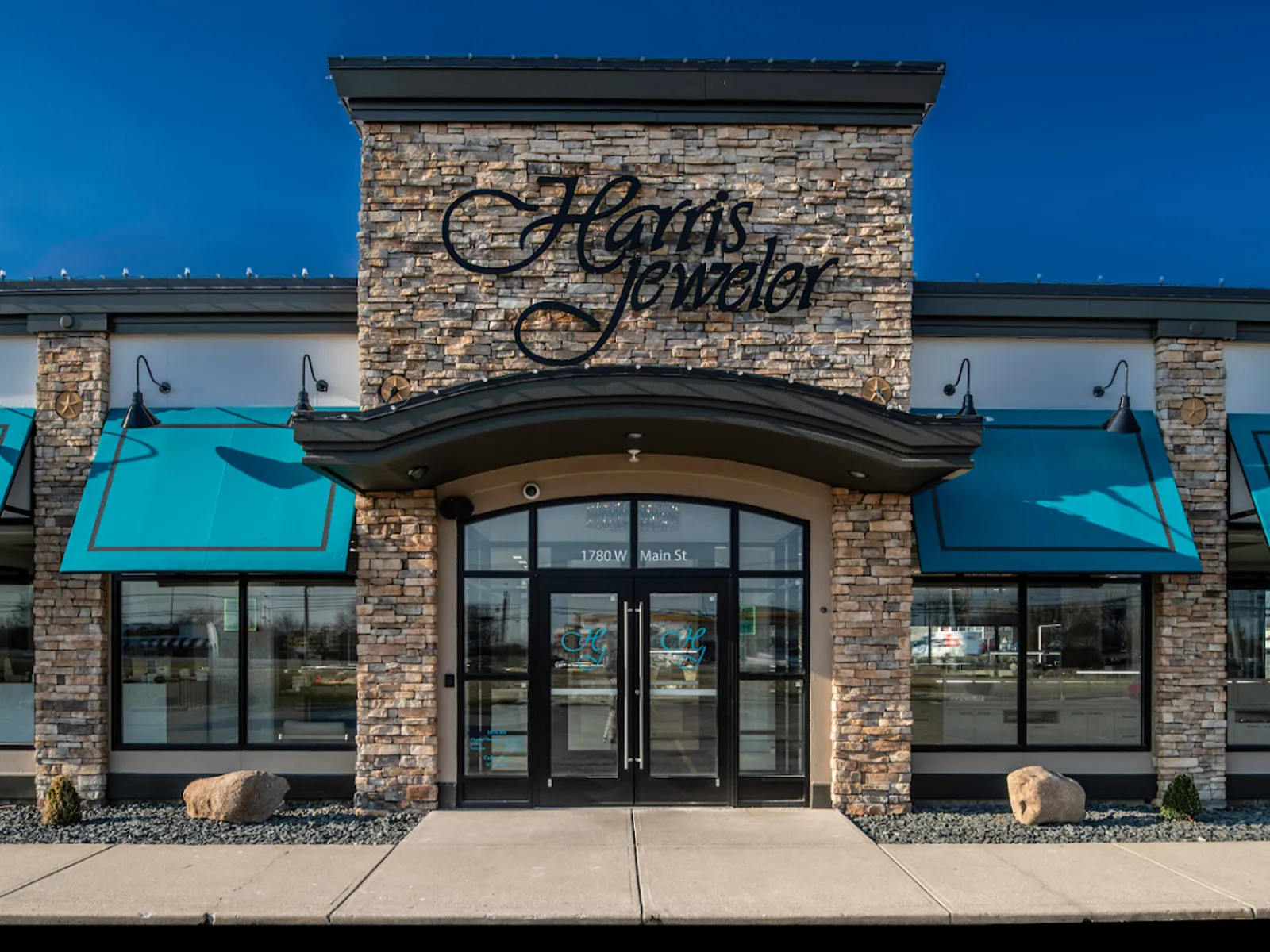 Storefront of Harris Jeweler with stone facade and teal awnings.
