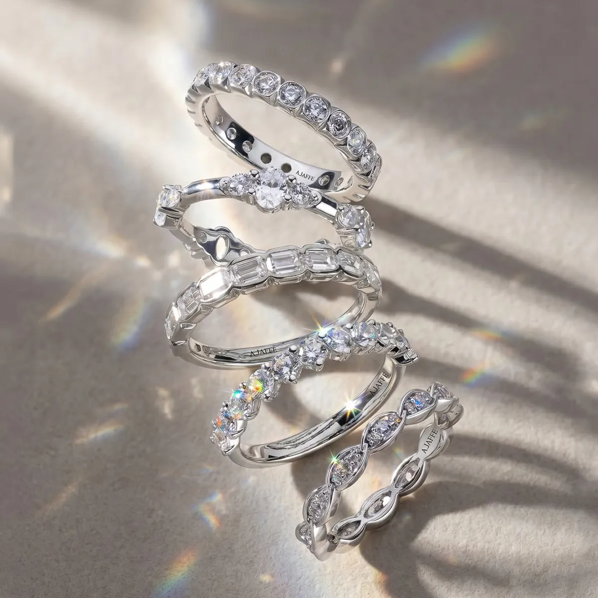 A stack of five sparkling diamond wedding bands on a textured surface.