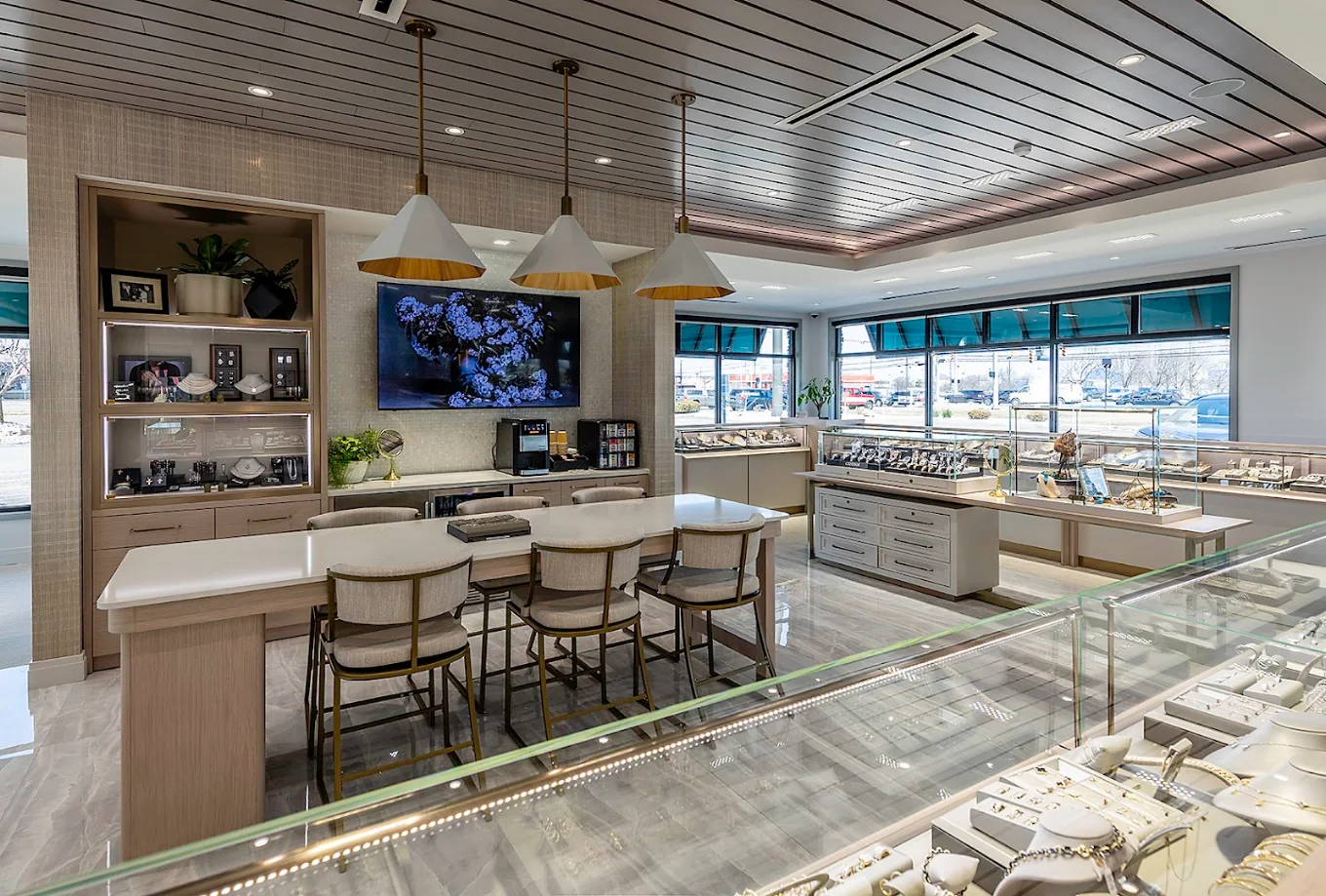 Modern jewelry store interior with display cases, seating area, and pendant lights.