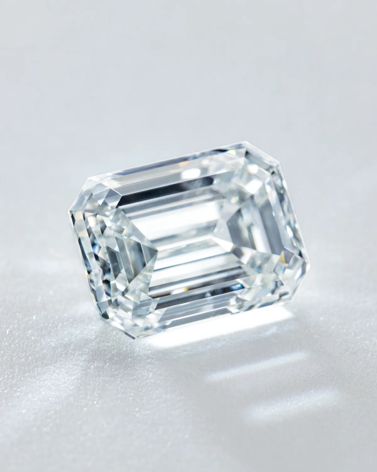 Emerald-cut diamond on a light surface, showcasing its clarity and facets.