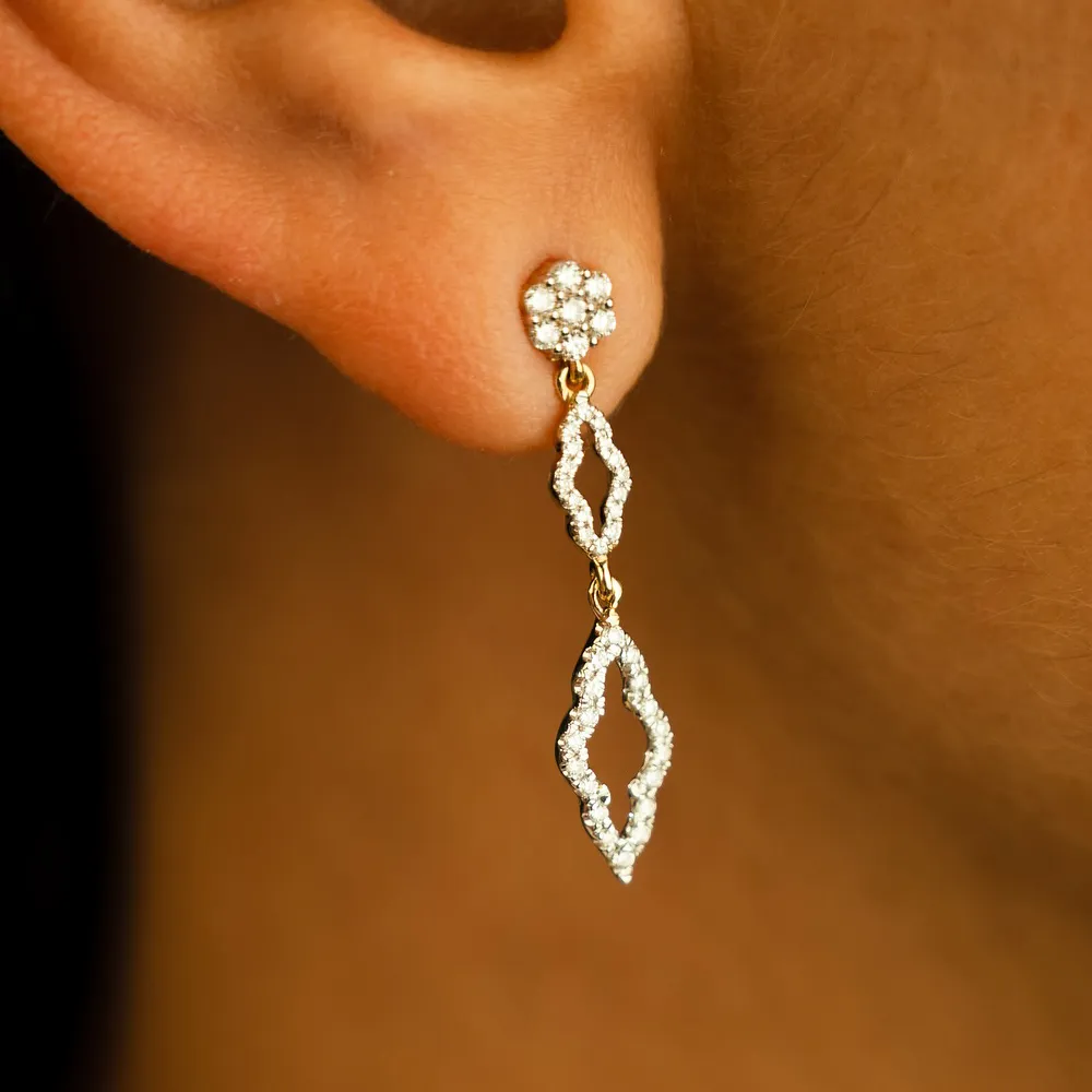 Elegant gold and diamond drop earrings displayed on an ear.
