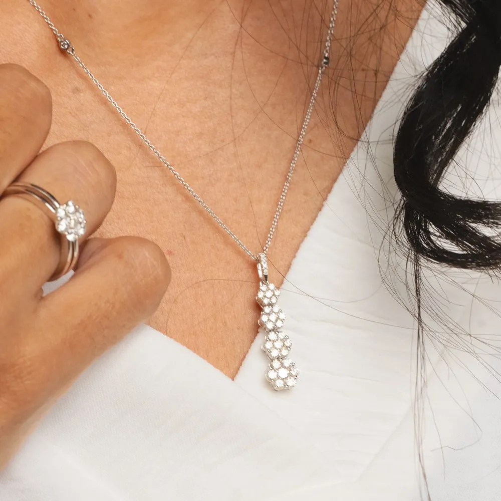 Close-up of a person wearing a diamond pendant necklace and ring.