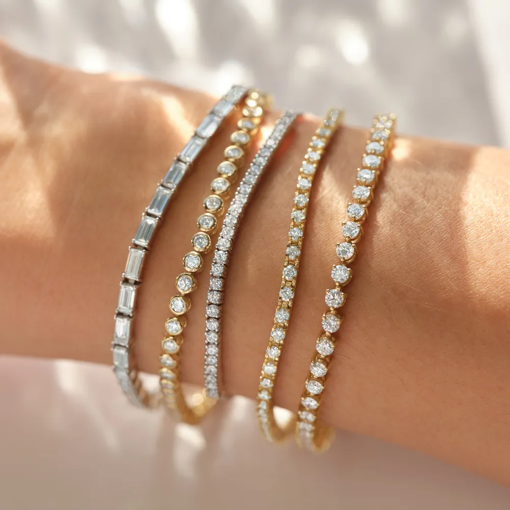 Elegant tennis bracelets with diamonds in gold and silver on wrist.