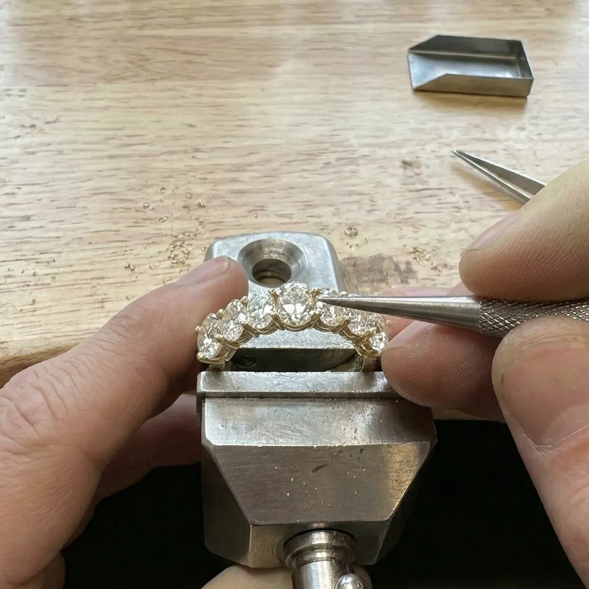 Jeweler crafting a diamond ring by hand on a workbench with precision tools.