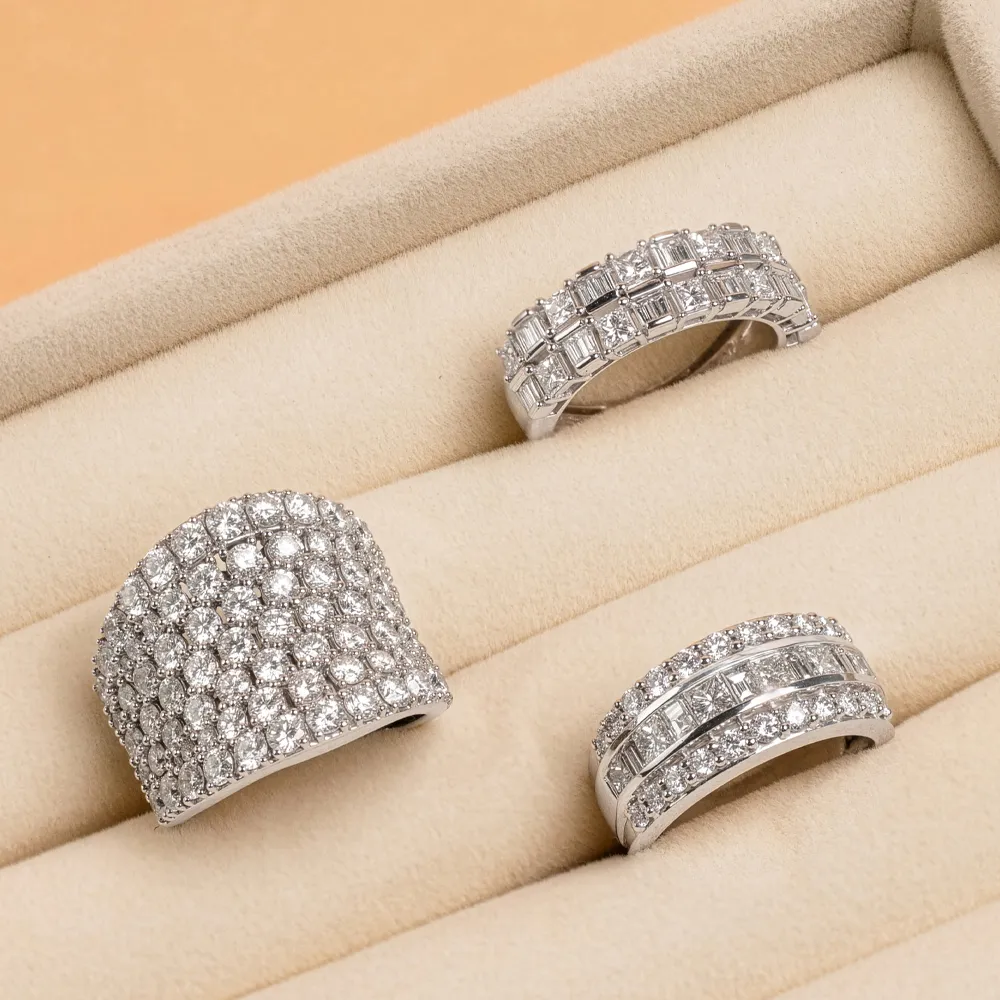Three diamond rings displayed on a beige jewelry tray.