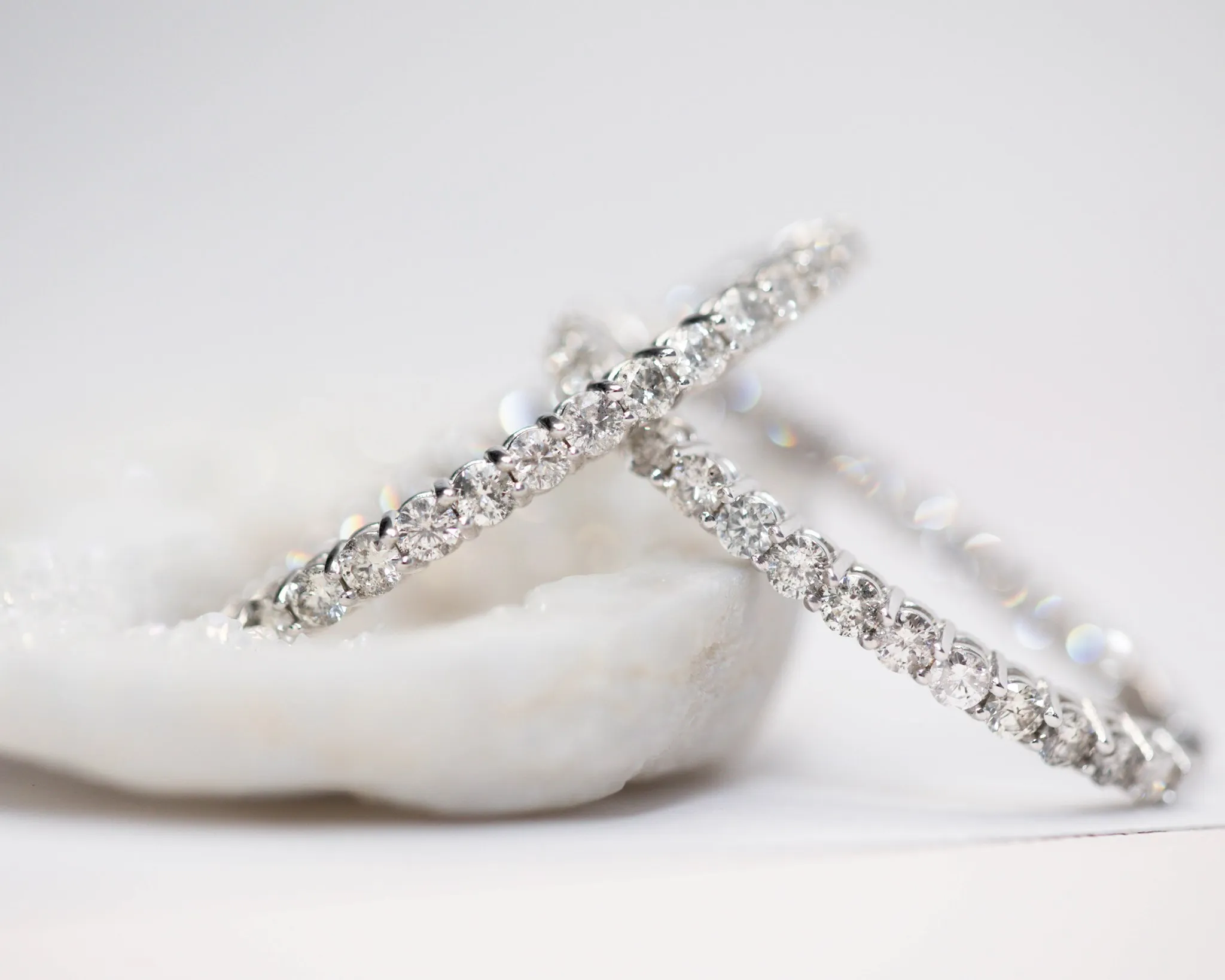 Silver necklace and earrings set with diamond accents on a soft, light background.