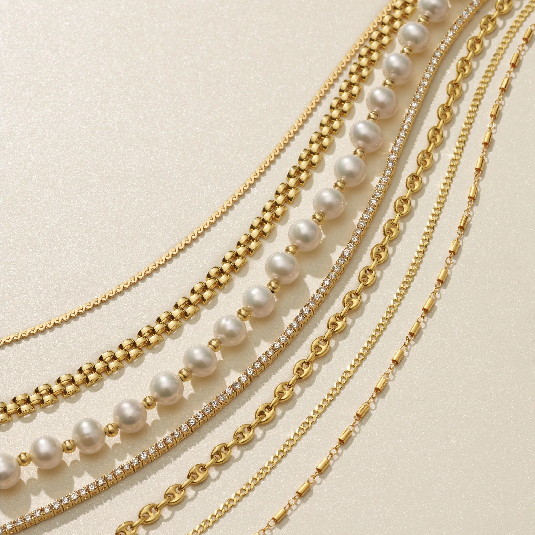 A gold necklace with a green gemstone pendant on a silky surface.