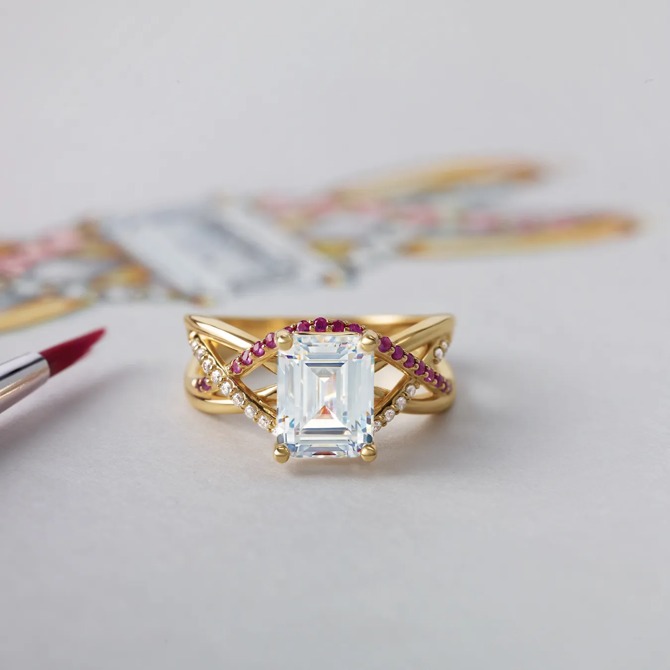 Gold ring with emerald-cut diamond, ruby, and diamond accents on a white background.