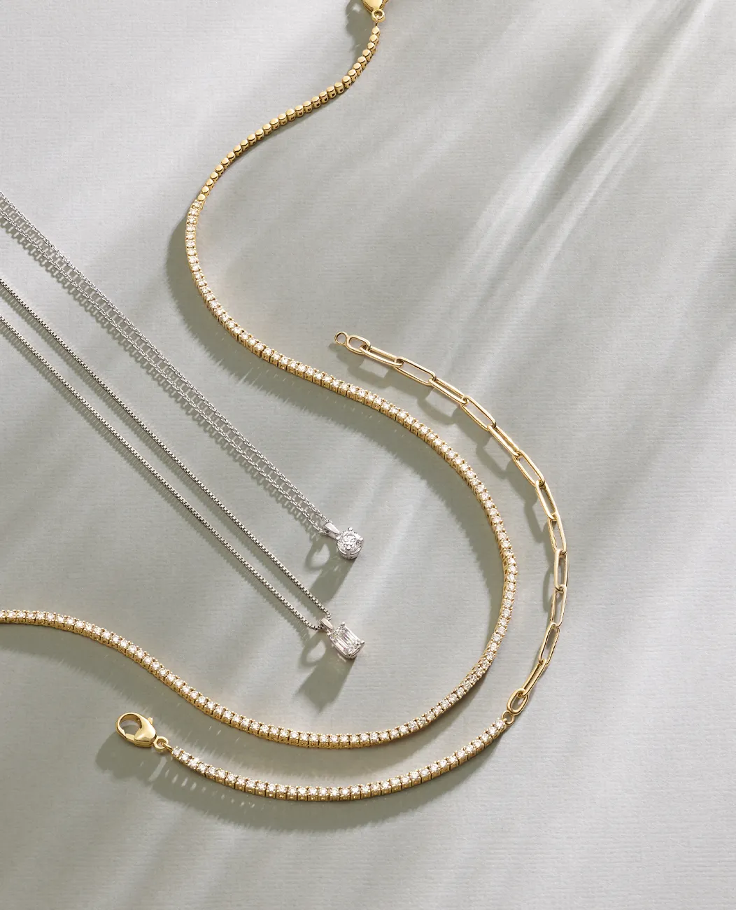 Elegant gold and silver chains and pendants on a soft background.