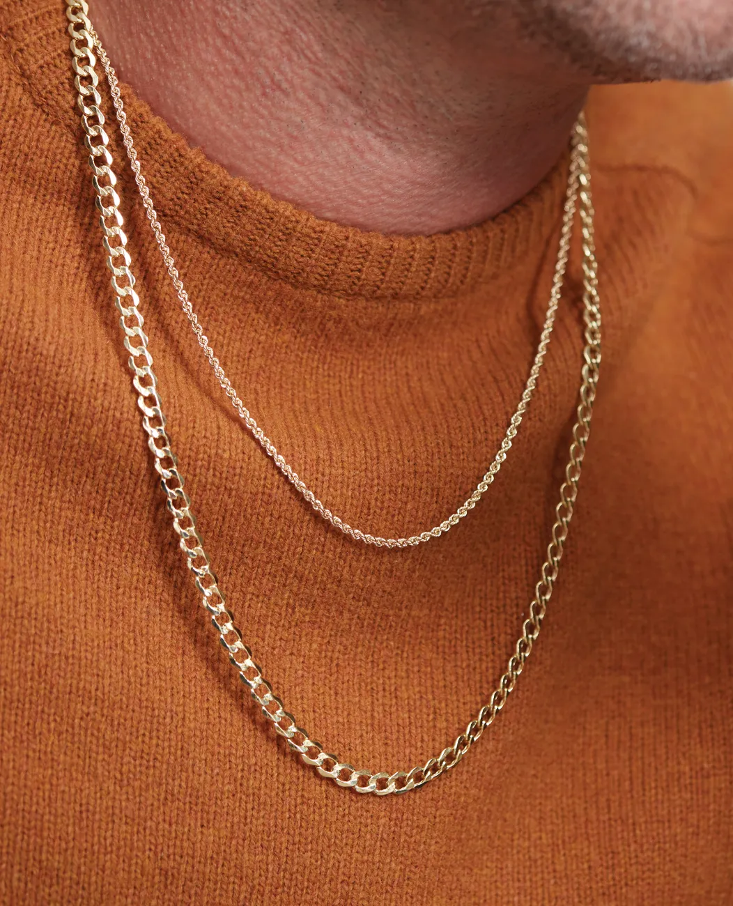 Gold chains layered over a brown sweater.
