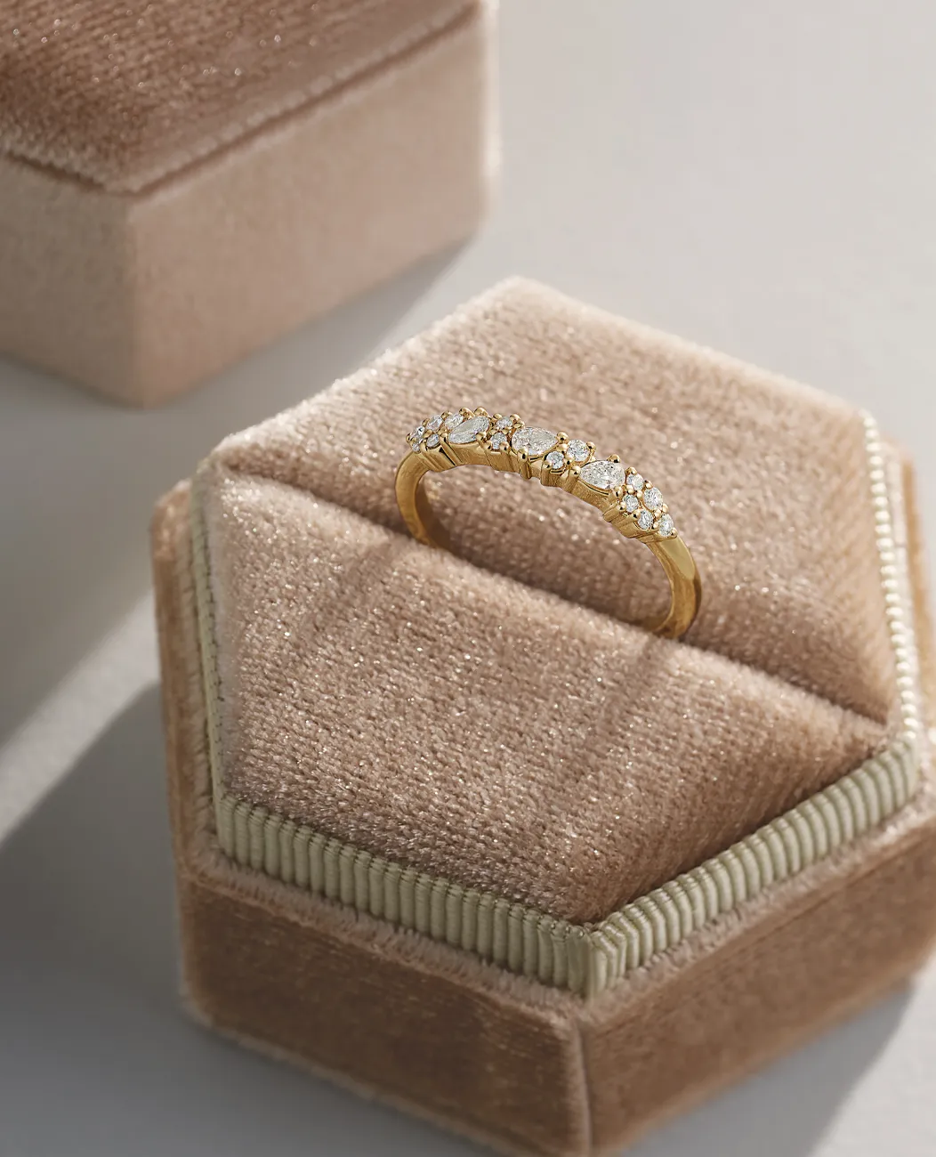 Gold ring with diamonds on a beige velvet box.