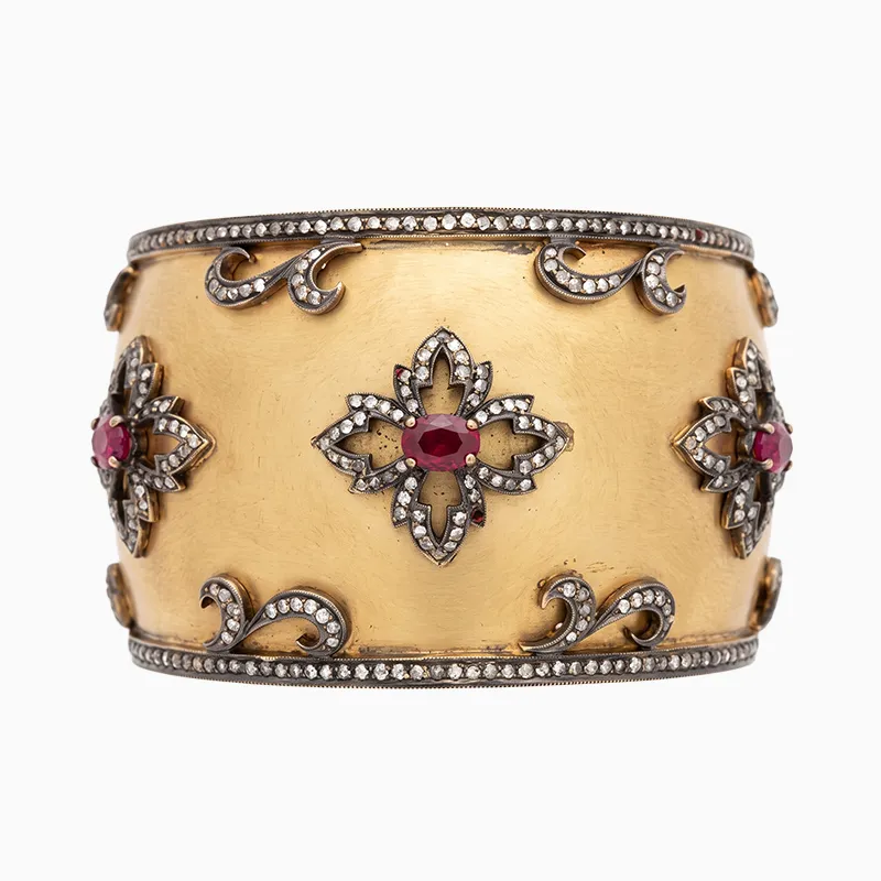 A gold cuff bracelet with ruby and diamond floral designs.