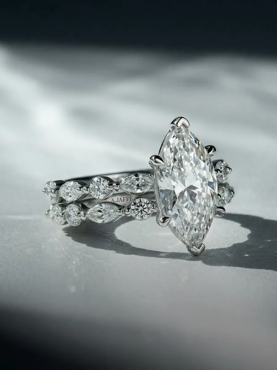 Marquise diamond ring with intricate band design on a reflective surface.