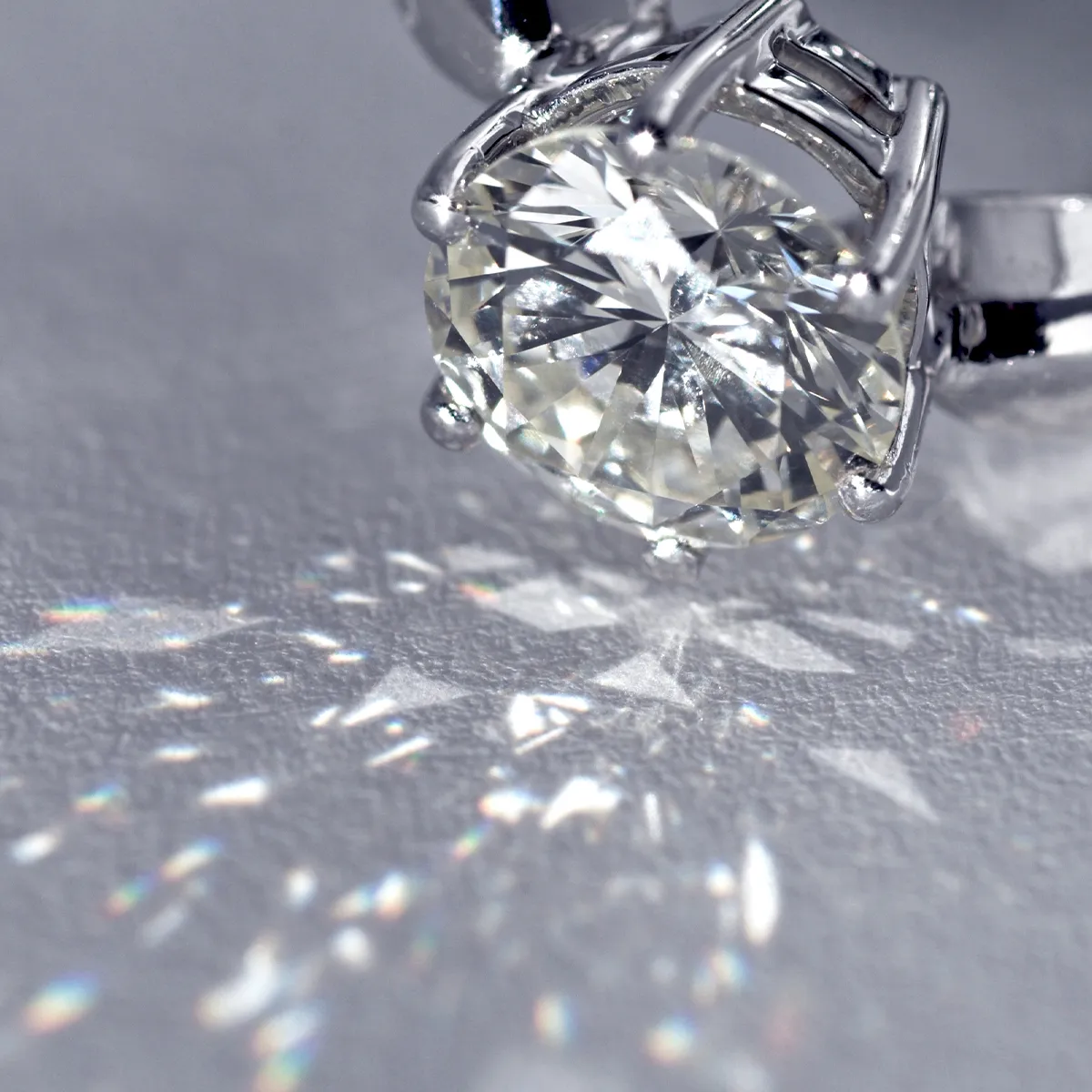 Close-up of a diamond ring with light reflections on a surface.