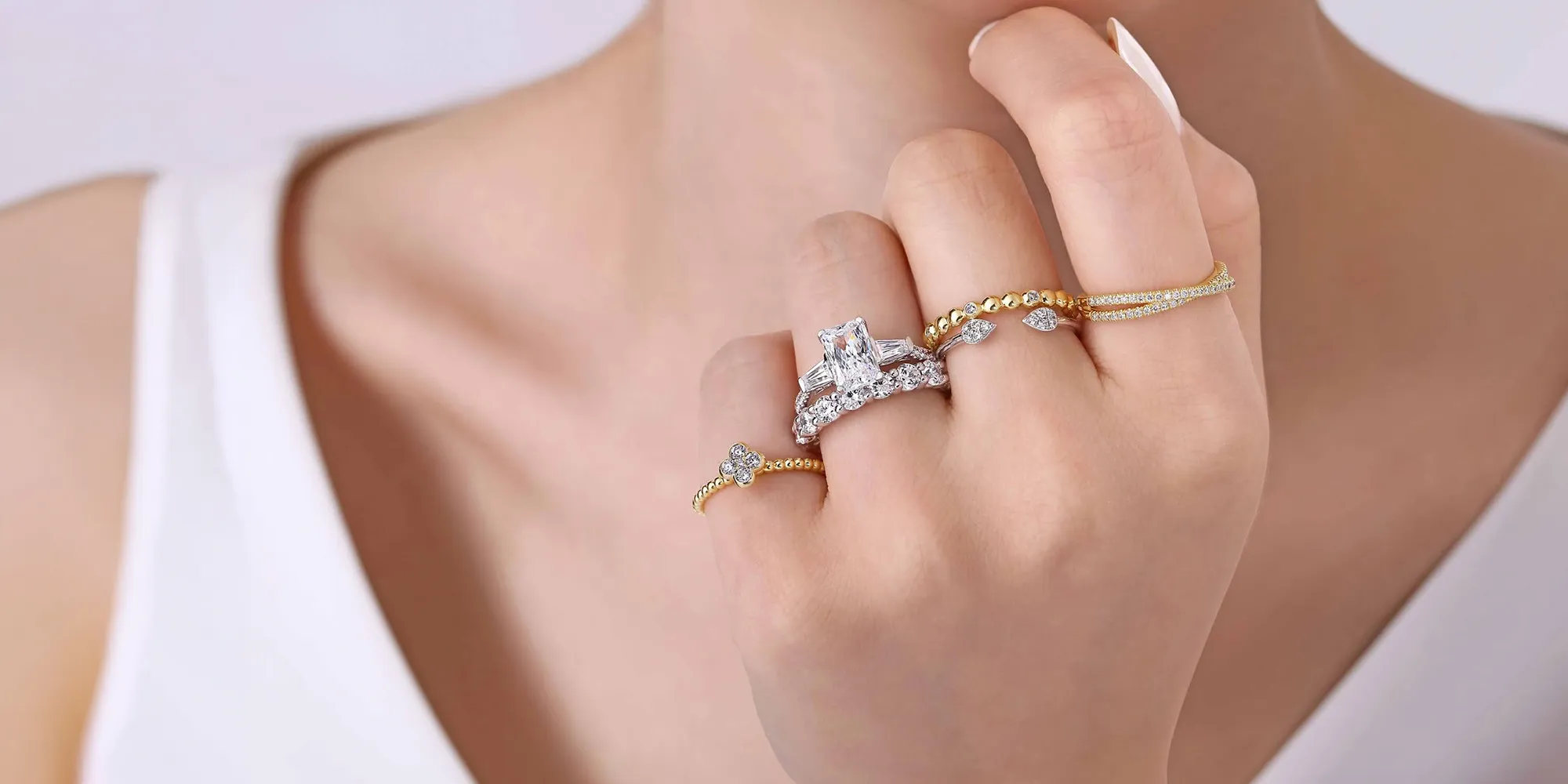 Hand adorned with multiple gold and diamond rings. Shop Gabriel & Co. Bridal.