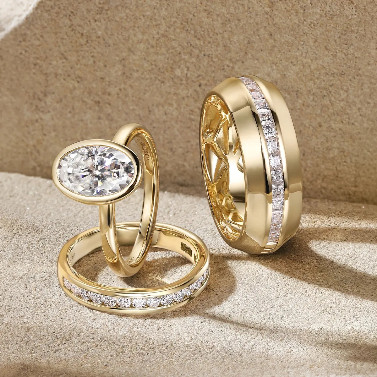 Gold rings with diamonds on a textured surface, showcasing bridal jewelry from Hingham Jewelers.