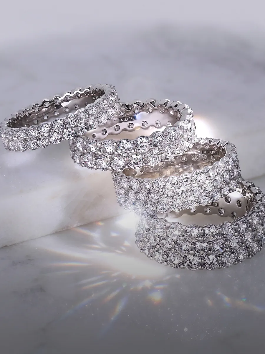 Diamond-studded wedding bands on marble surface, available at Hingham Jewelers.