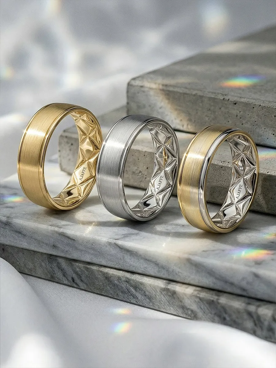 Three elegant rings on stone slabs, featuring gold and silver tones with diamond accents.