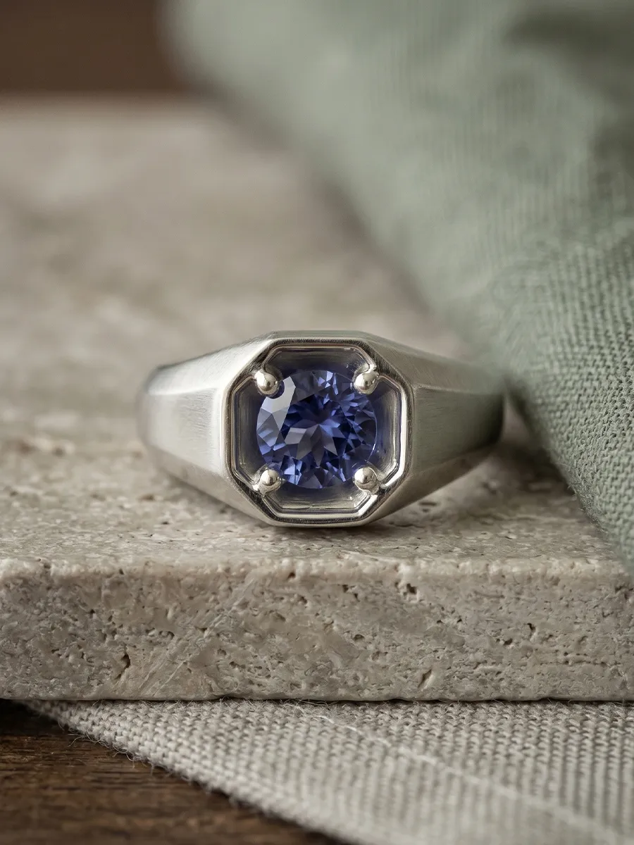 Silver ring with a blue gemstone set on a textured stone surface.