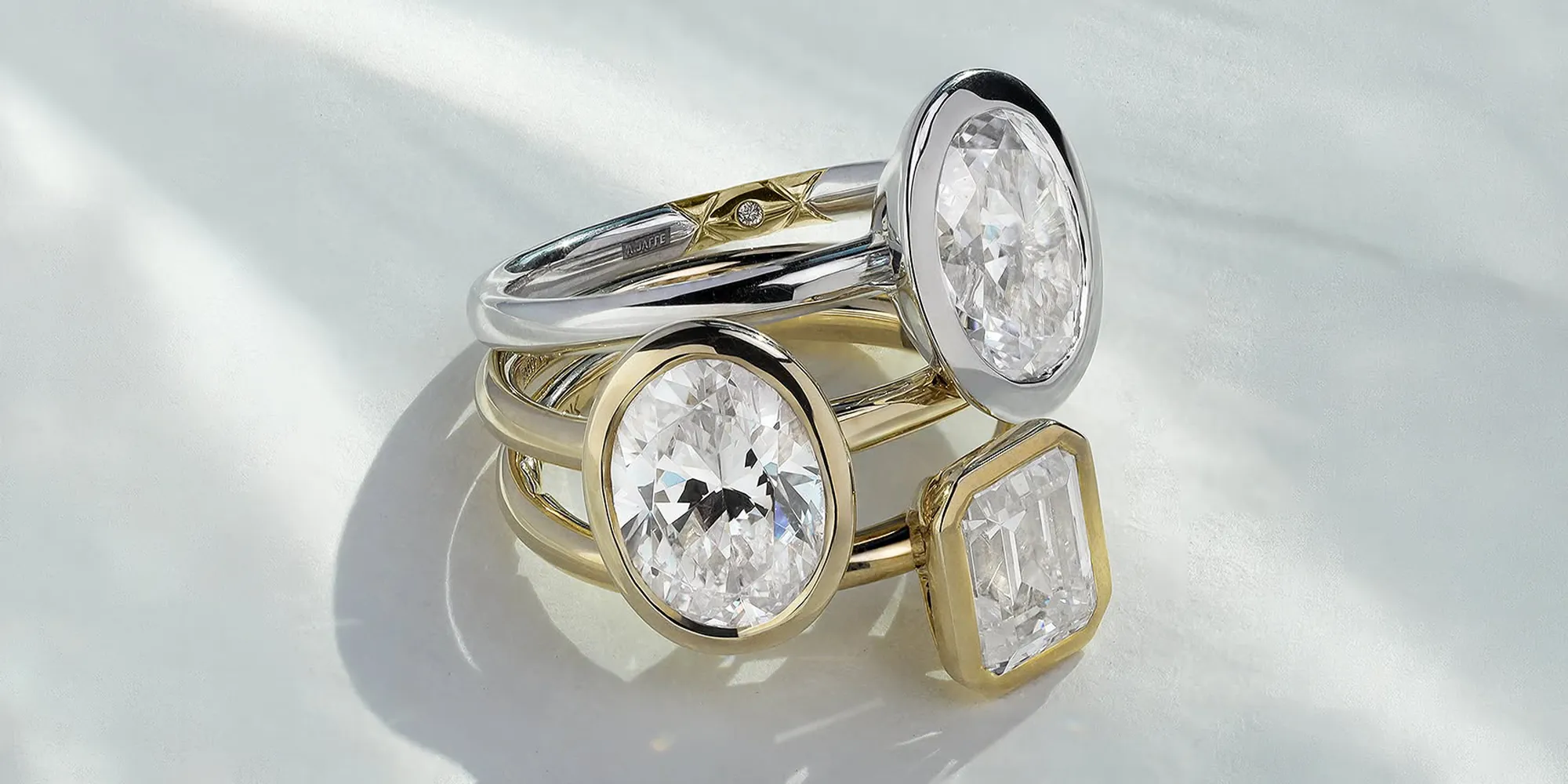 Three diamond rings with gold and silver bands on a light surface.