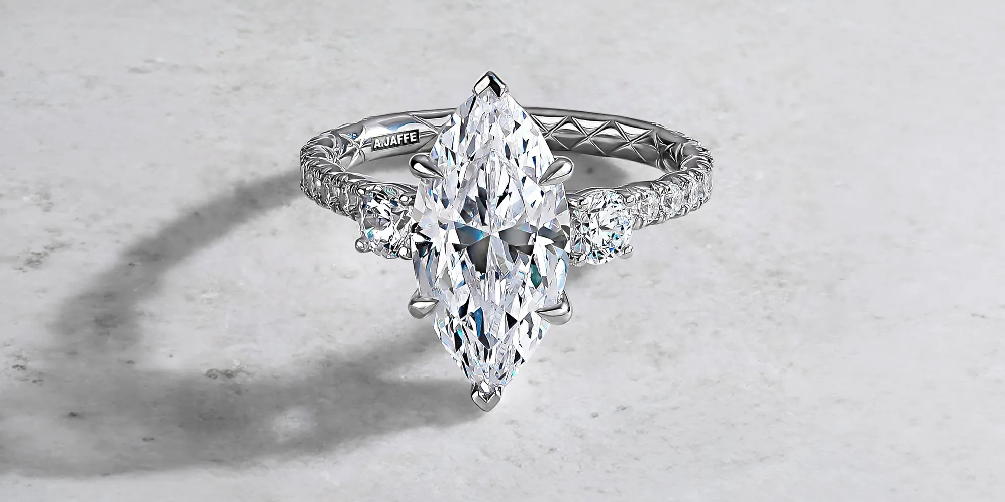 Marquise-cut diamond ring with intricate band design on a light surface.