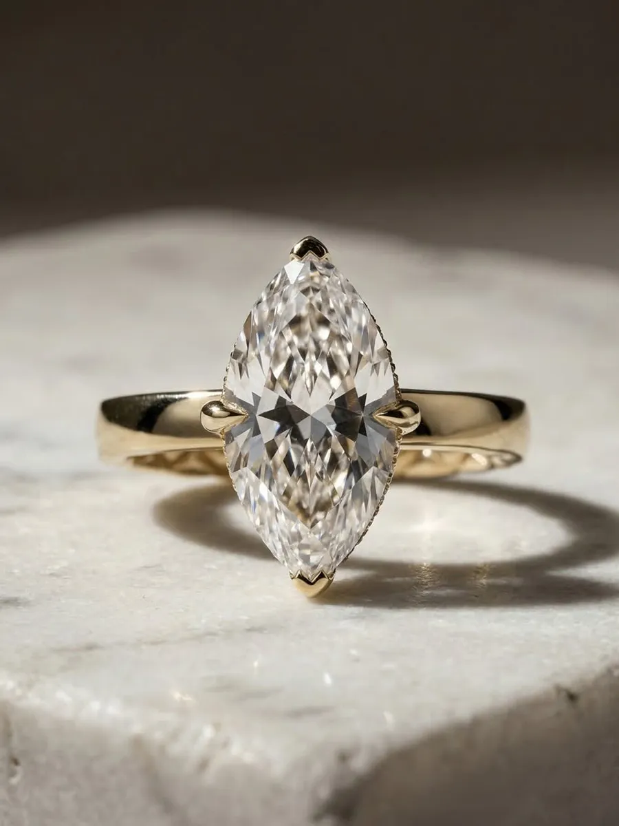 A marquise-cut diamond ring with a gold band on a marble surface.