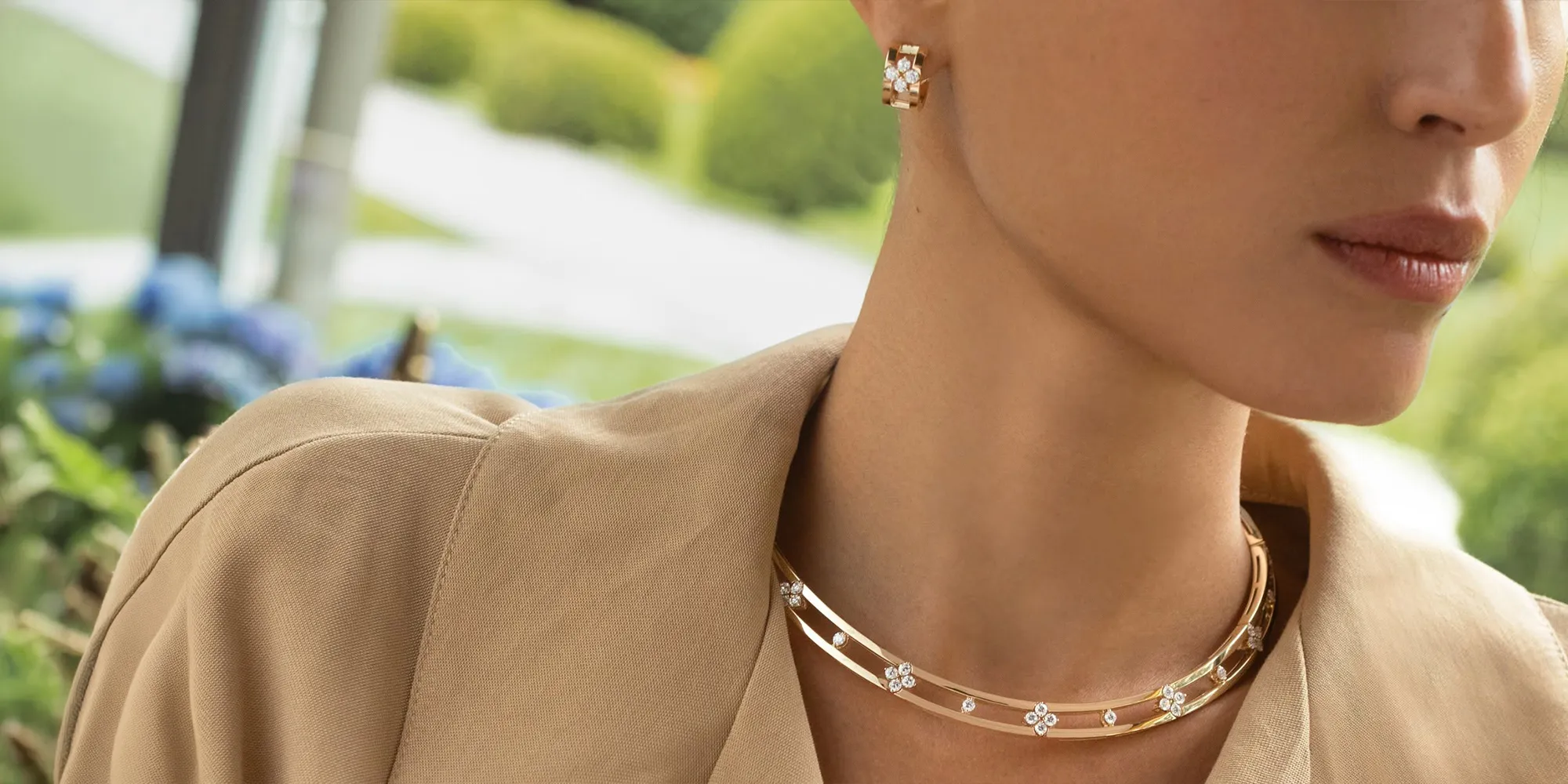 Elegant woman wearing gold necklace and earrings with floral design.