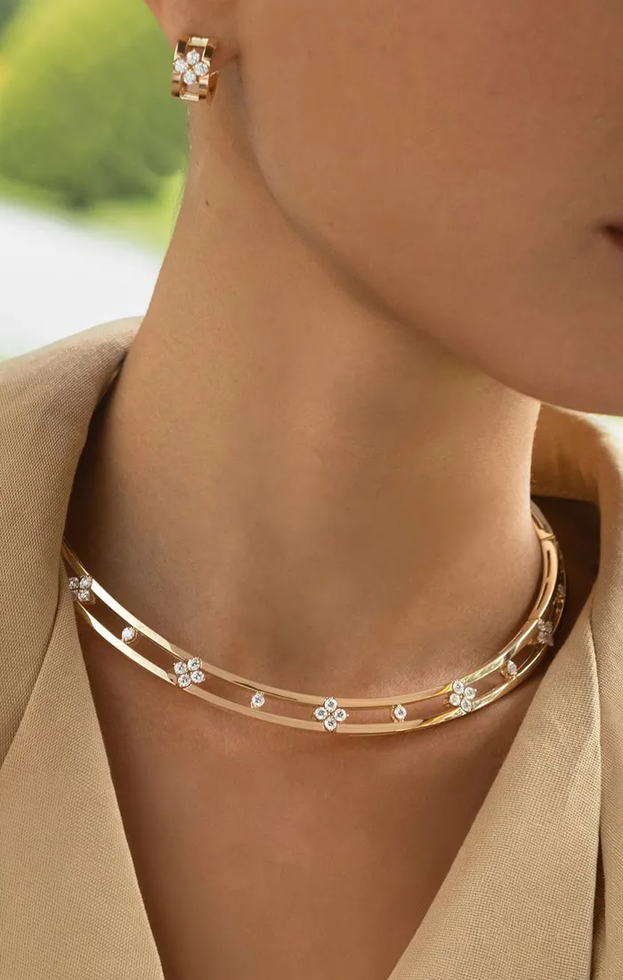 Elegant woman wearing gold necklace and earrings with floral design.