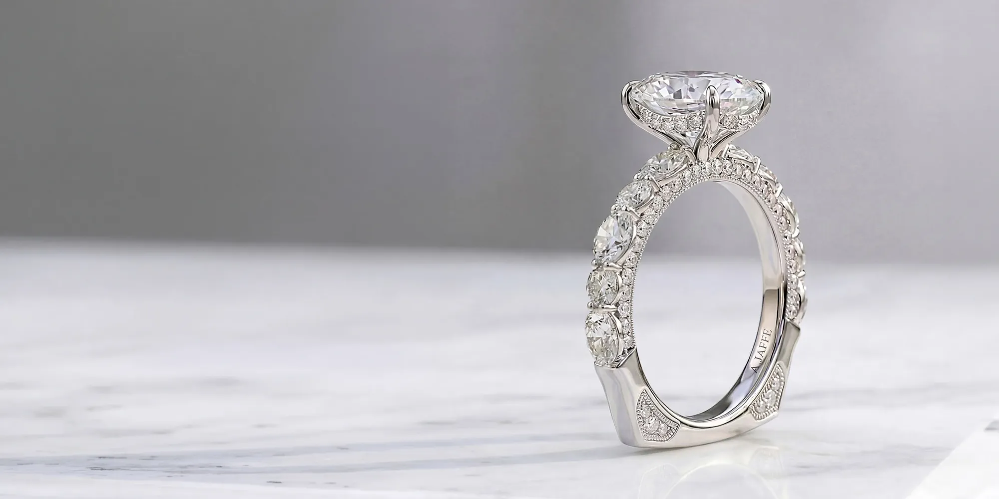 Diamond engagement ring with intricate band on marble surface. Shop Engagement Rings.