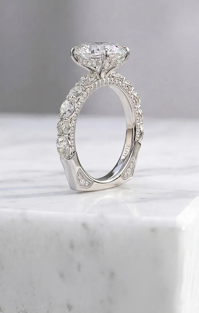 Diamond engagement ring with intricate band on marble surface. Shop Engagement Rings.