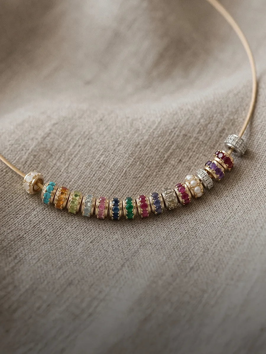 Colorful gemstone and pearl necklace on a beige fabric background.