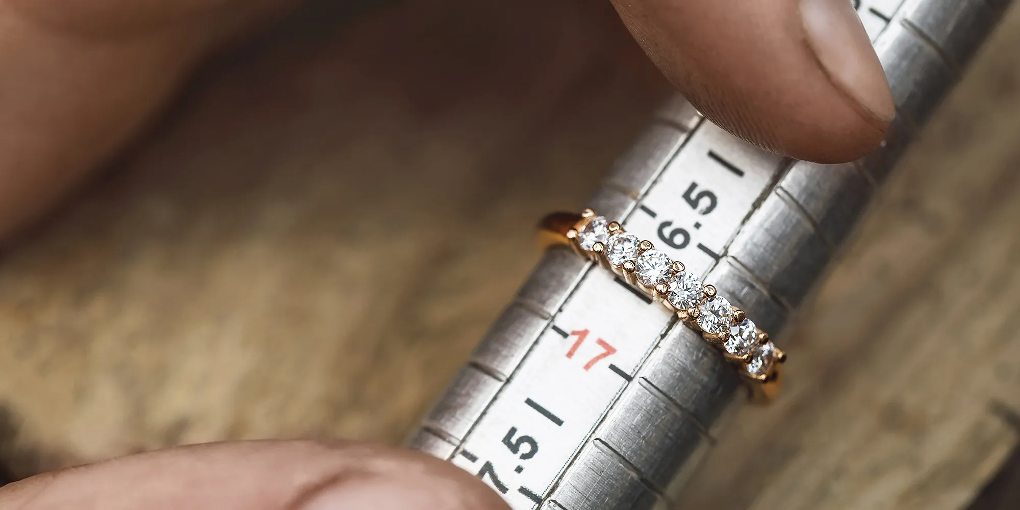 A ring with diamonds is measured on a metal ring sizer.