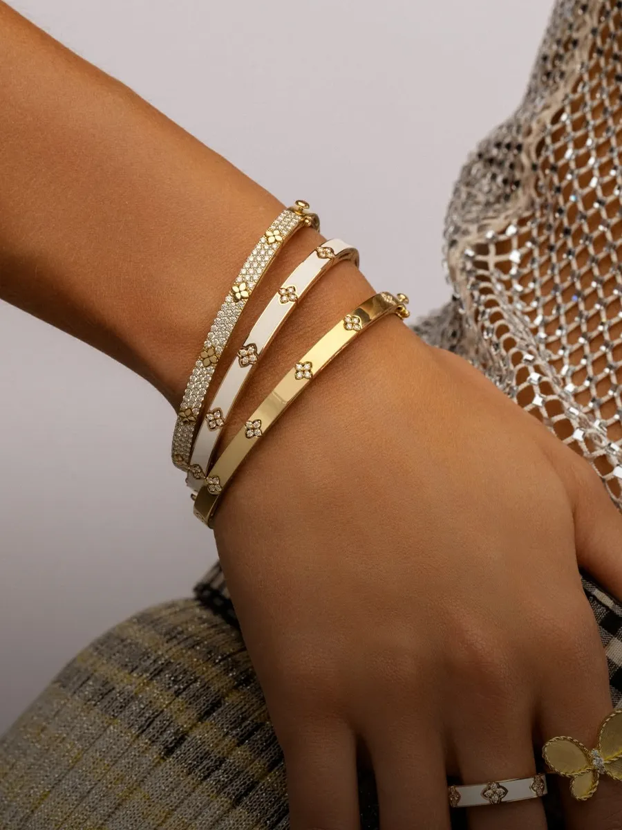 Stacked gold and diamond bracelets on a wrist. Shop bracelets at Hingham Jewelers.