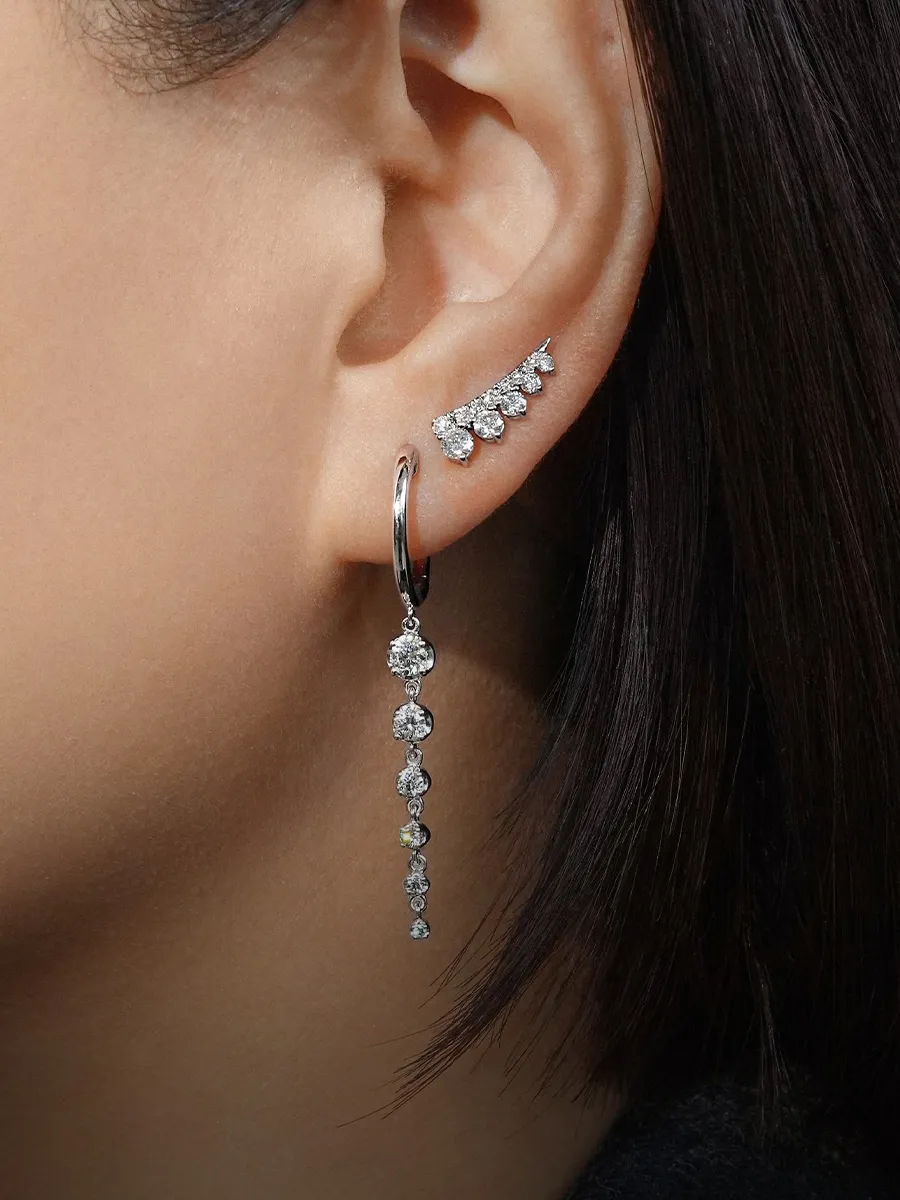 Close-up of an ear with diamond drop and stud earrings. Shop earrings at Hingham Jewelers.