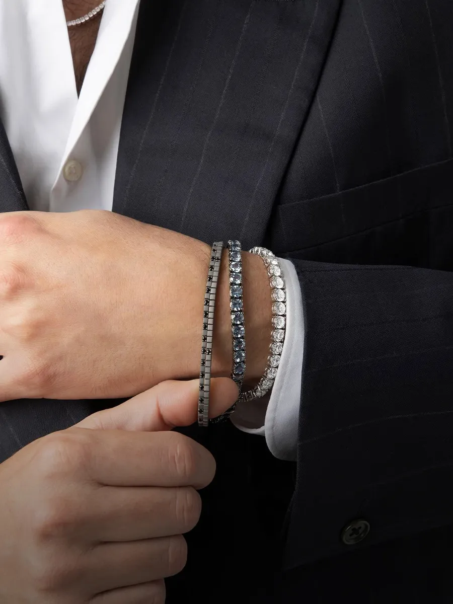 Man in a suit wearing multiple diamond bracelets. Shop men's jewelry at Hingham Jewelers.