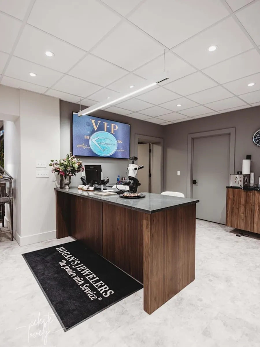 Modern jewelry store interior with a wooden counter, flowers, and a VIP sign on the wall.