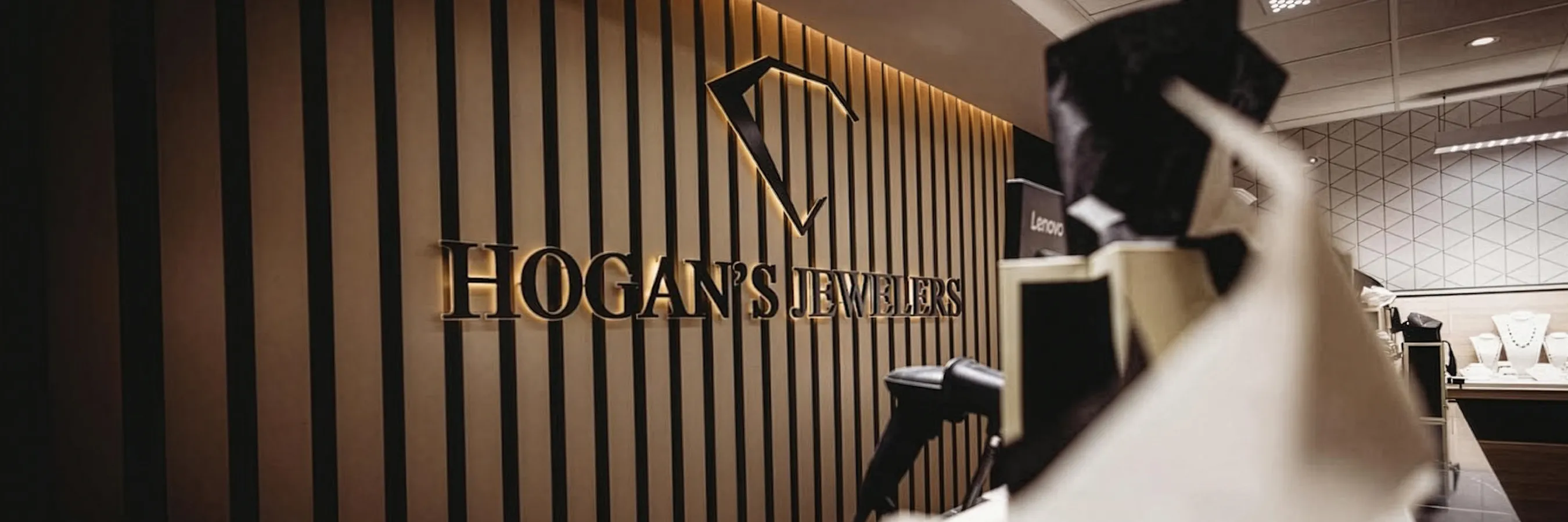 Hogan's Jewelers logo on a striped wall inside a jewelry store.