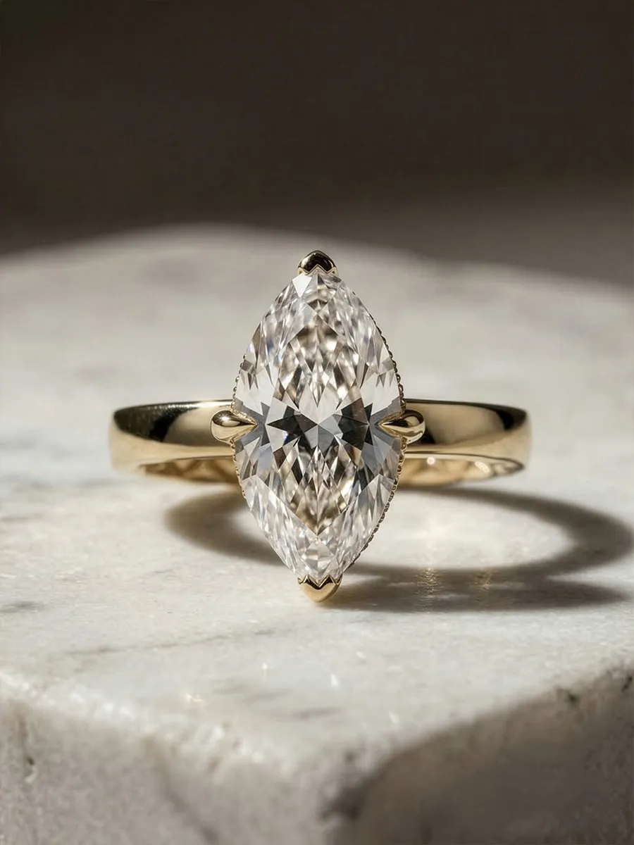 A marquise-cut diamond ring with a gold band on a marble surface.