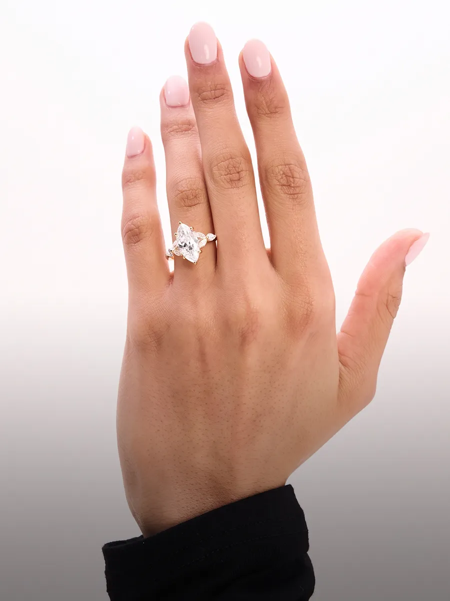 A hand with a manicured nail wearing a large diamond engagement ring.