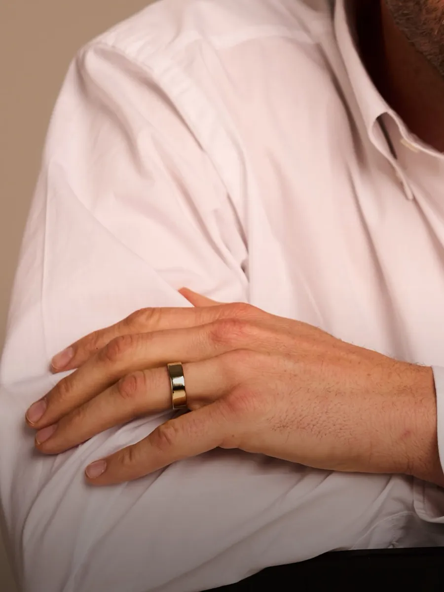 A person in a white shirt with a gold wedding band on their hand.