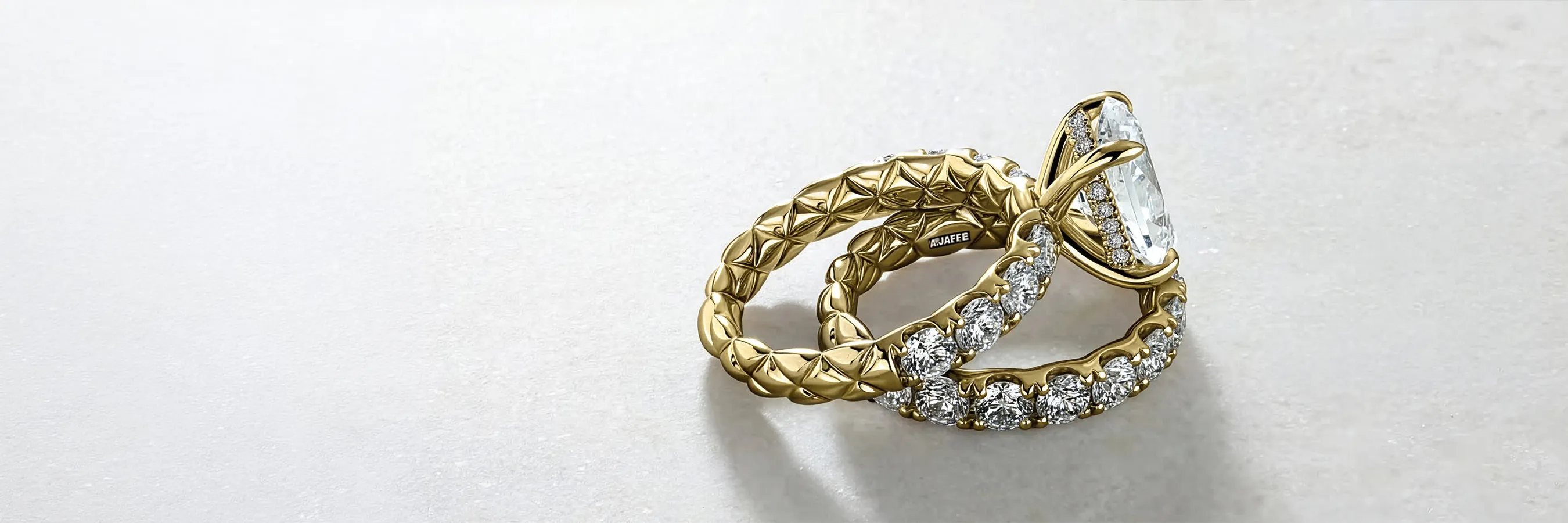 Gold engagement ring with diamond accents and a large center stone on a light background.