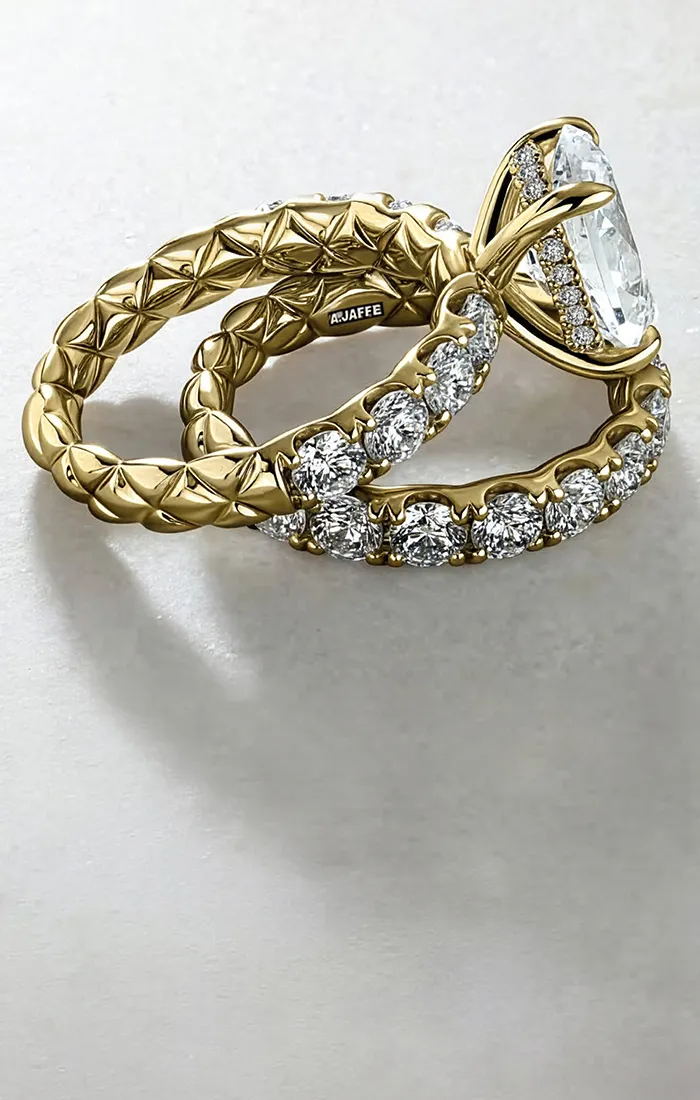 Gold engagement ring with diamond accents and a large center stone on a light background.
