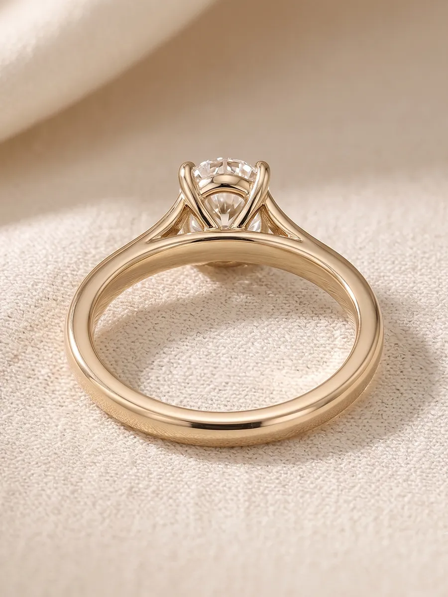 A gold engagement ring with a solitaire diamond on a textured fabric background.