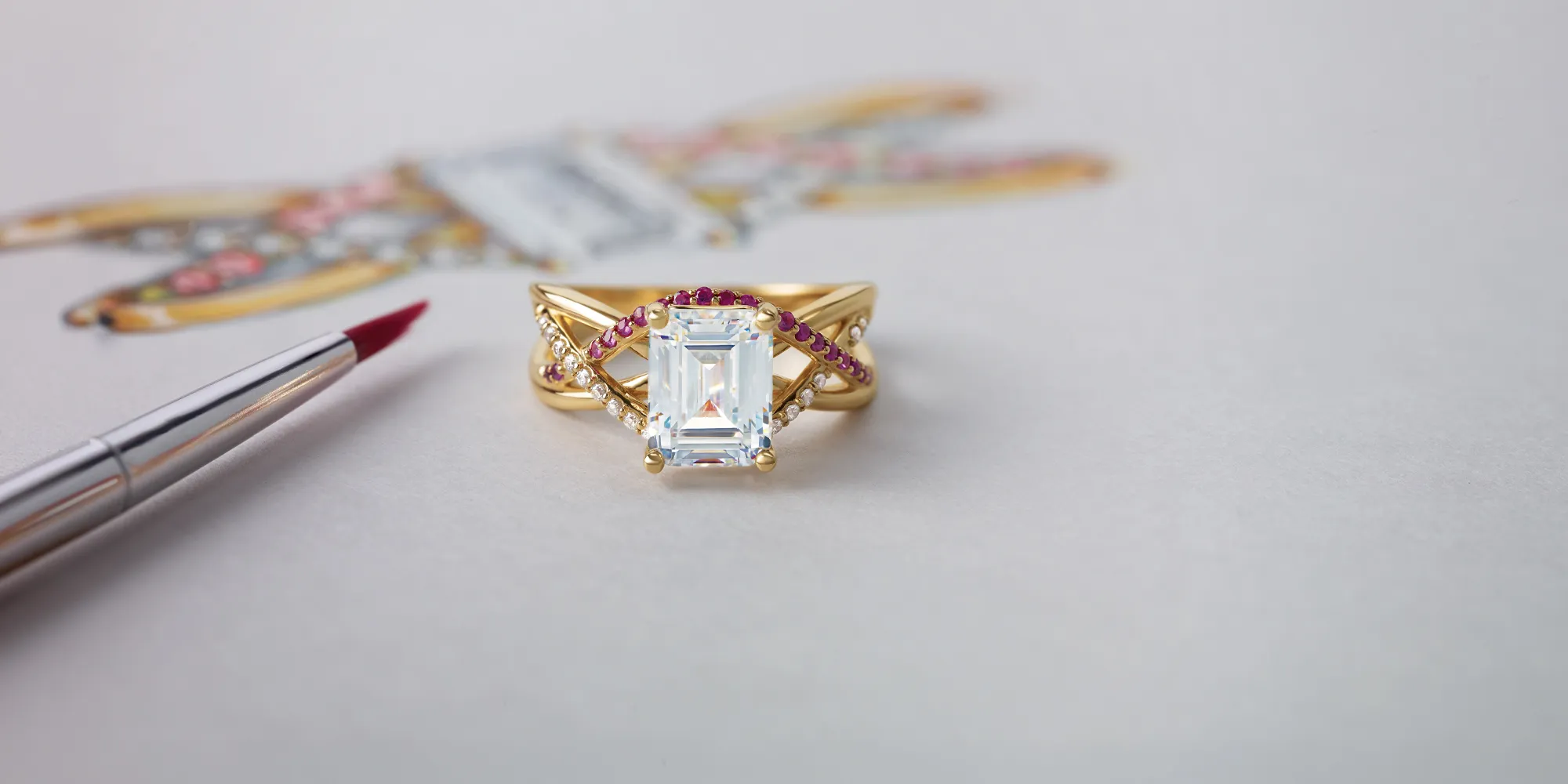 A gold ring with a large emerald-cut diamond, accented by red and white stones, on a light background.