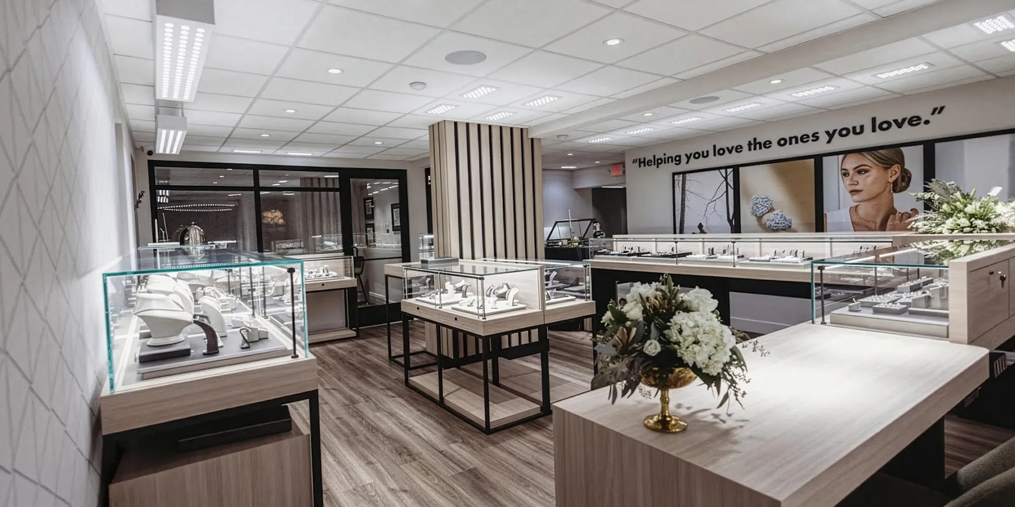 A modern jewelry store interior with glass display cases and floral arrangements.