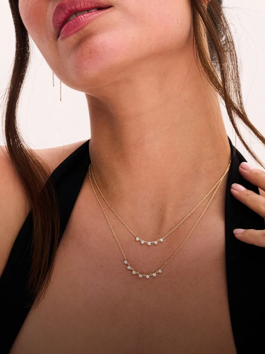 A woman wearing layered gold necklaces with small gemstones, close-up view.