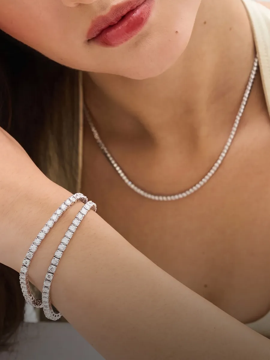 A woman wearing a diamond necklace and two diamond bracelets on her wrist.